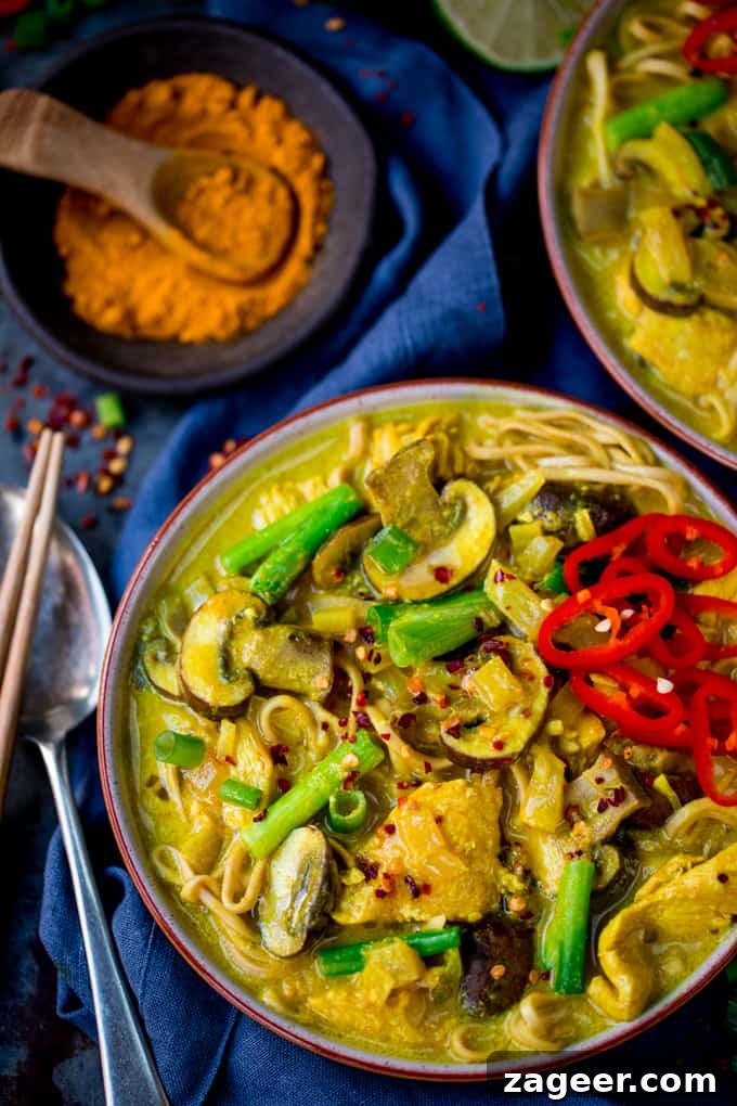 Turmeric Chicken Noodle Soup Recipe for Immunity Boost 4 overhead close up photo of a bowl of Chicken Noodle Soup with Turmeric on a dark background with turmeric in the background