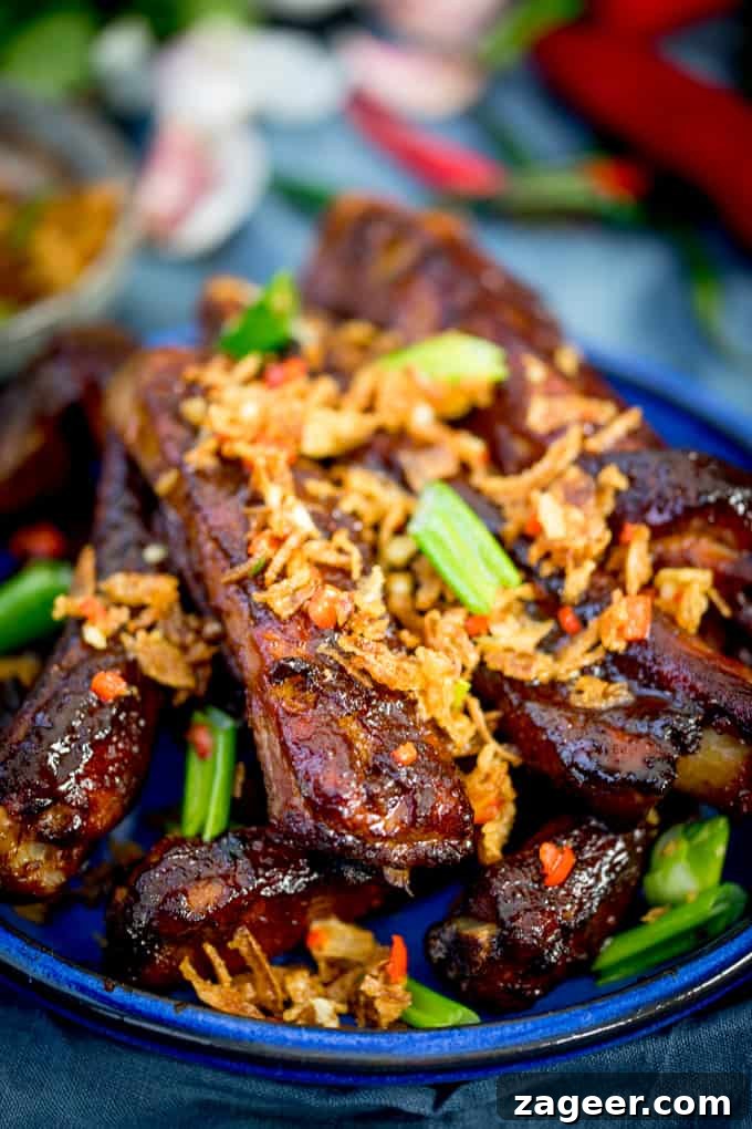 Crispy Onion Oven-Baked Asian Ribs Recipe 4 Close up of Oven Baked Asian Ribs with Crispy Onions on a blue plate with spring onions