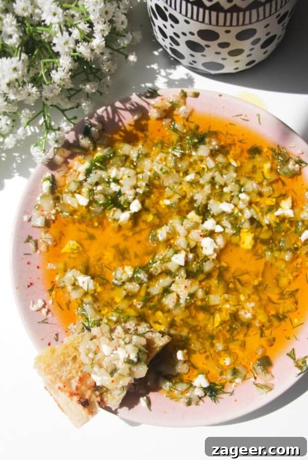 Dill pickle dipping oil on a pink plate with a piece of focaccia on the side.