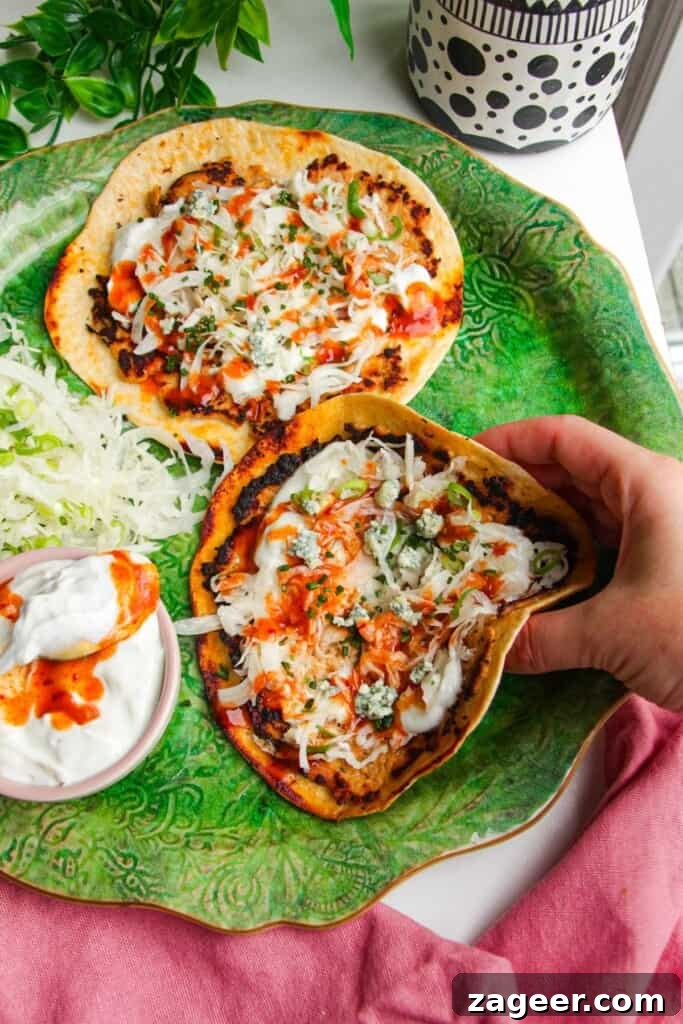 Hand picking up buffalo chicken smash taco from platter.