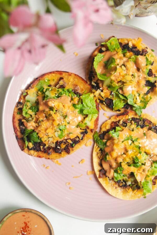 Three smash cheeseburger tacos on a pink plate.