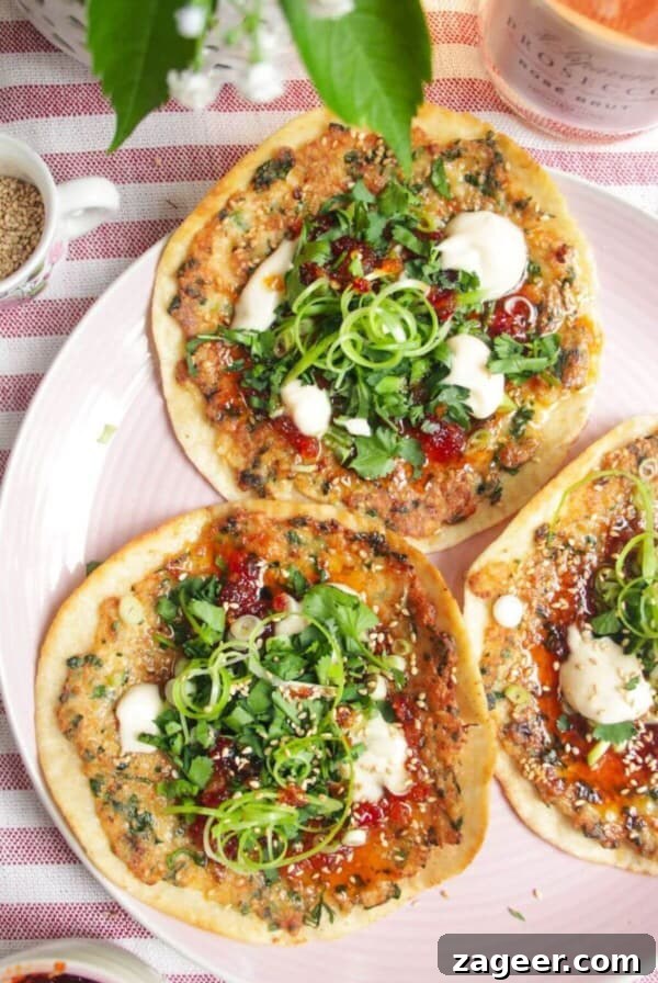 Three prawn toast tacos topped with herbs and aioli on a pink plate.