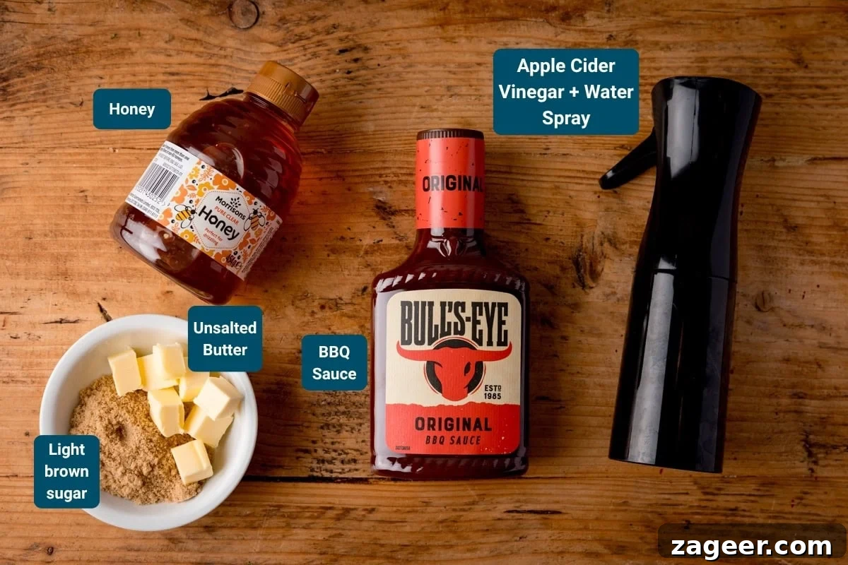 A bottle of honey, a bowl with light brown sugar and unsalted butter, a bottle of BBQ sauce, and a spray bottle labelled apple cider vinegar + water on a wooden table.