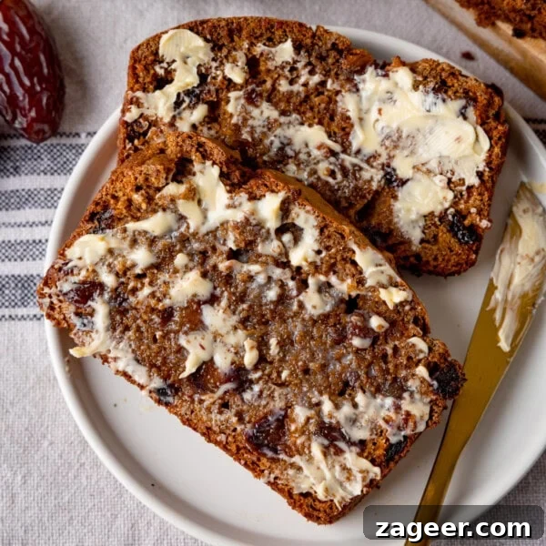 Two slices of malt loaf with butter spread on top, served on a white plate.
