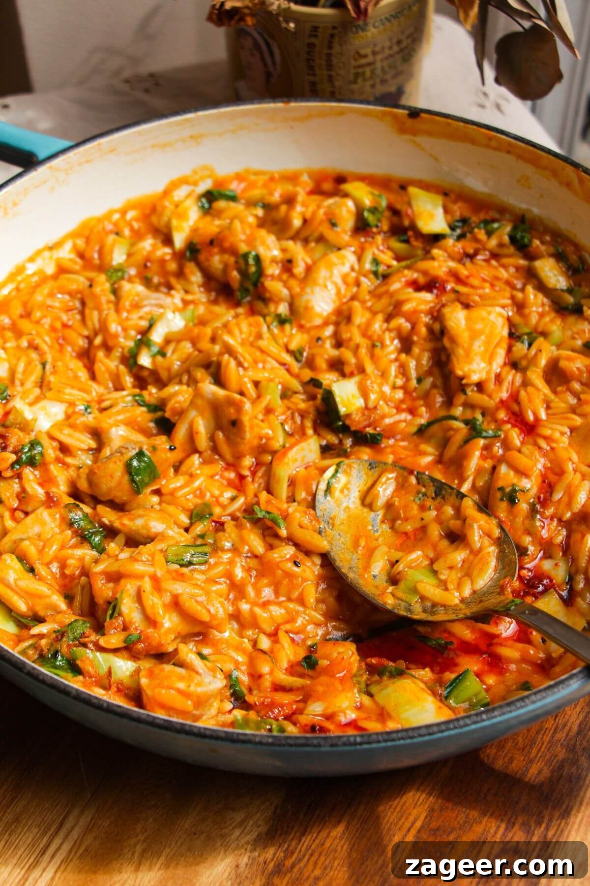One-Pot Thai Red Curry Chicken Orzo for Weeknight Dinners 2 Red curry chicken orzo in a pan with a spoon.