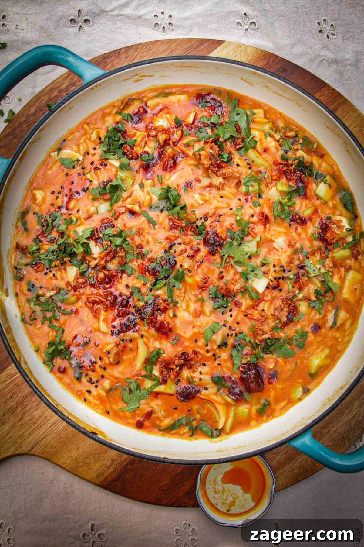 One-Pot Thai Red Curry Chicken Orzo for Weeknight Dinners 11 Red curry chicken orzo in a pan, drizzled with chili oil.