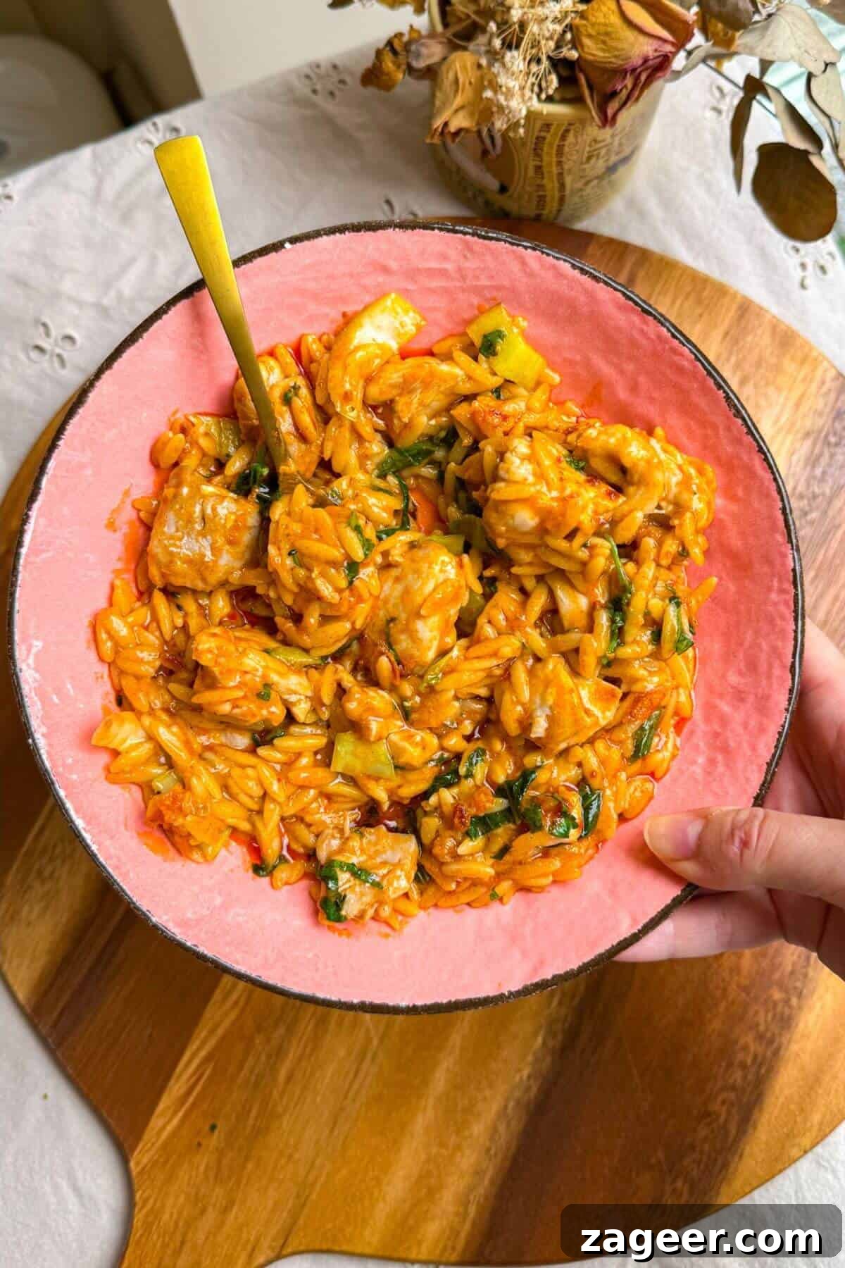 One-Pot Thai Red Curry Chicken Orzo for Weeknight Dinners 12 Holding a plate of red curry chicken orzo.