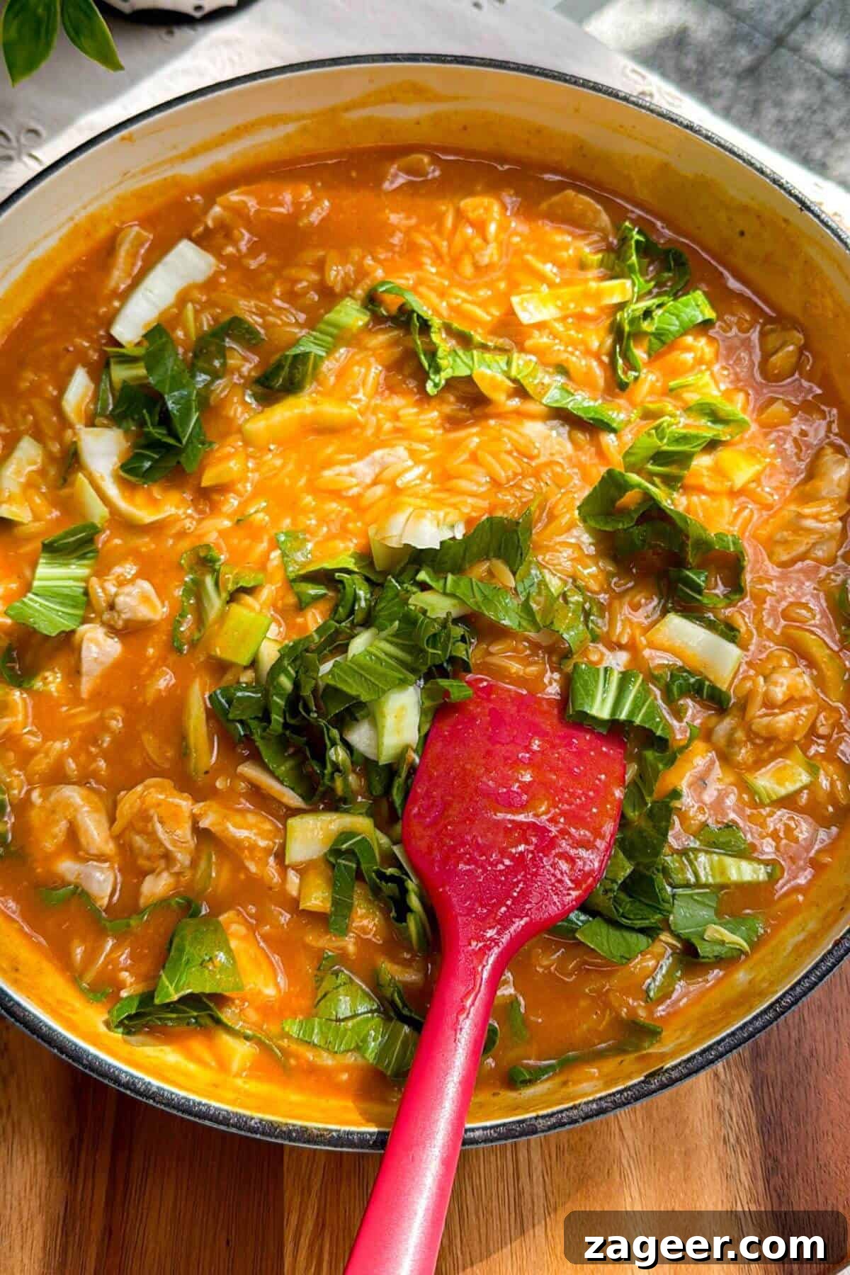 One-Pot Thai Red Curry Chicken Orzo for Weeknight Dinners 10 Pak choi added to red curry orzo in a pan.