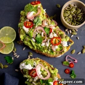 Two pieces of loaded avocado toast with feta, shallot, sliced red chilli, seeds and coriander.